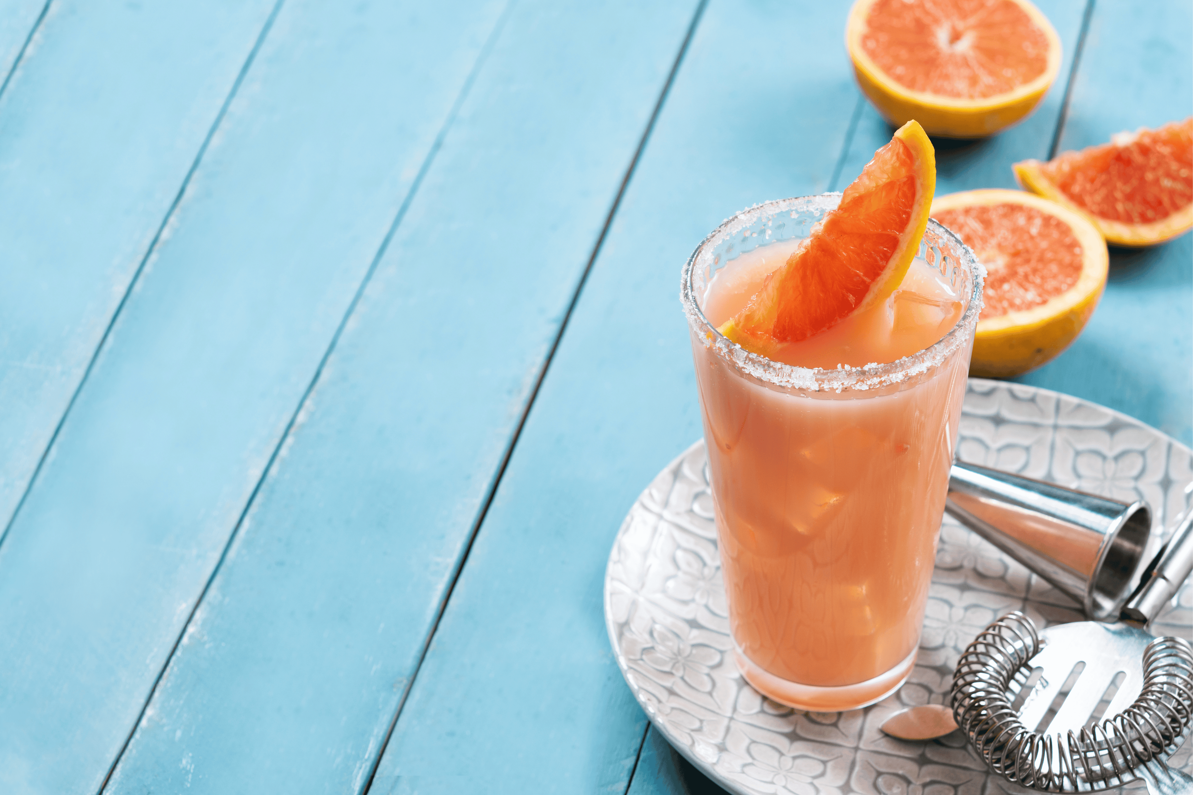 PALOMA AUF BLAUEM TISCH MIT BAR EQUIPMENT UND GRAPEFRUIT AUFGESCHNITTEN